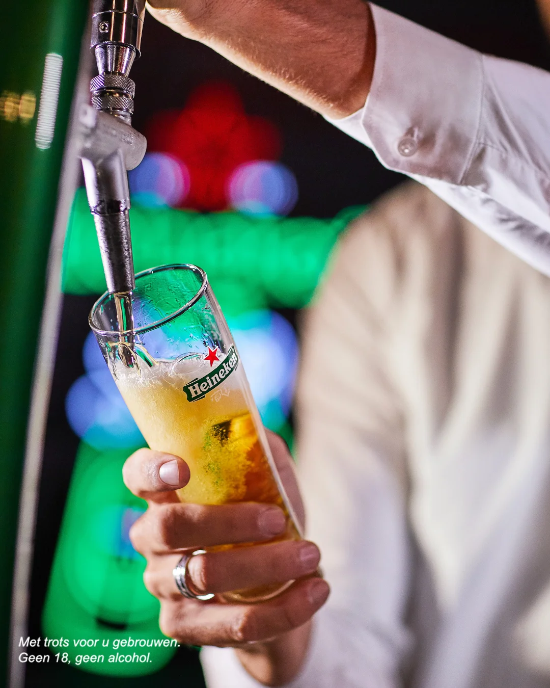 Pack de bières Heineken 0.0% avec une bouteille et une canette sur une table, et un pack de six en arrière-plan.