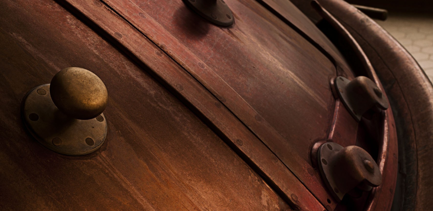 Intérieur d'une brasserie avec de grandes cuves en cuivre alignées et une décoration industrielle, avec un sol en mosaïque."